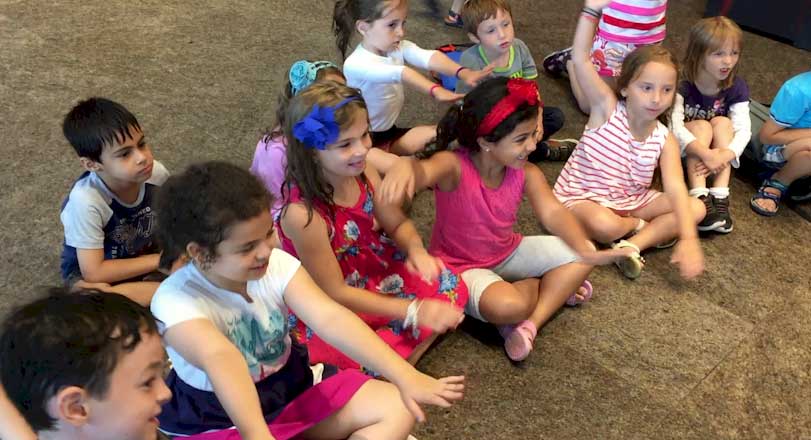 Children sitting together on the floor, smiling.
