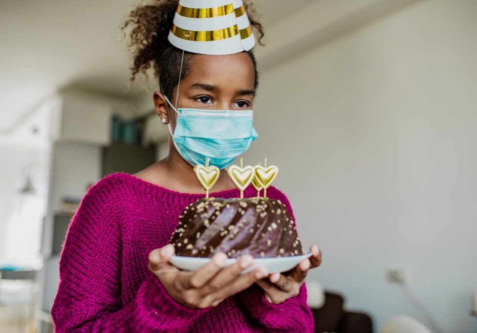 Child holding cake and wearing hat